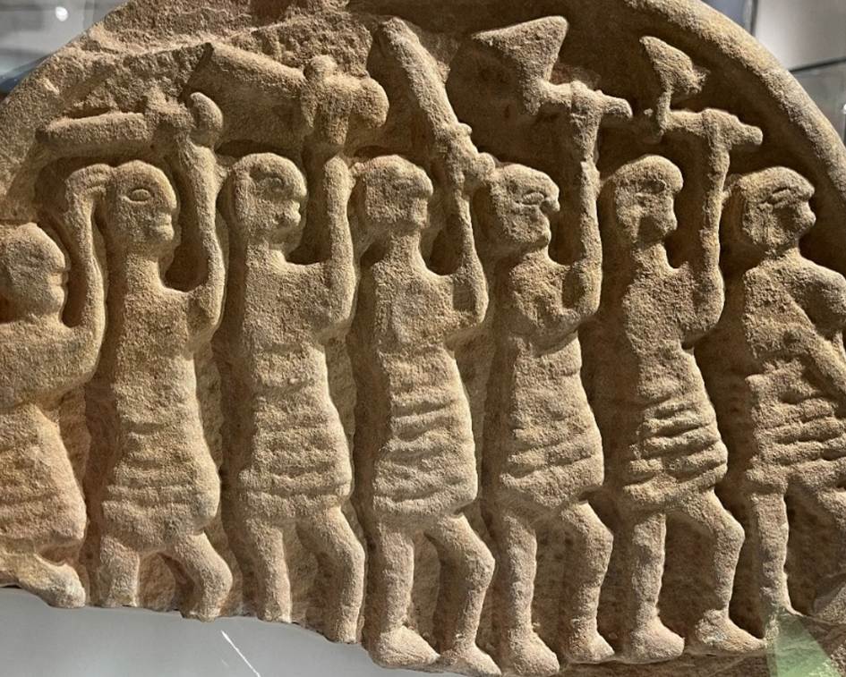 A stone carving of people in a room
Description automatically generated